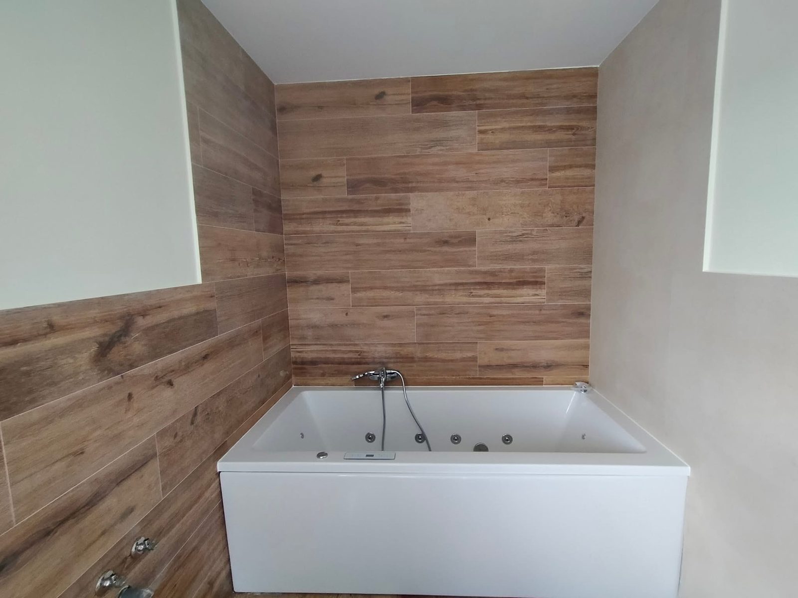 Baño reformado con bañera de hidromasaje y revestimiento imitación madera
