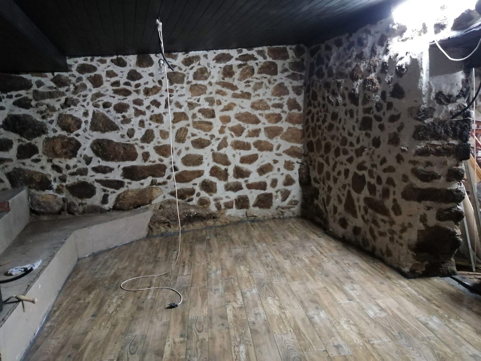 Muro de piedra recuperado en el interior de una casa con suelo de madera